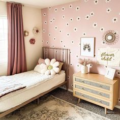 a bedroom with pink walls and white flowers on the wall