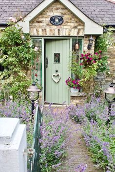 a green door surrounded by purple flowers and greenery