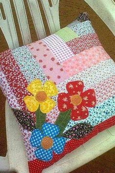 a white chair sitting next to a pillow with flowers on it