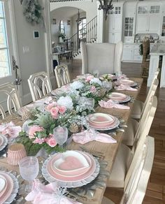 the table is set with pink and white plates, flowers and napkins on it