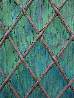 an old rusty fence with green paint on it