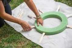 a person is making a wreath out of popsicle sticks on the ground with their hands