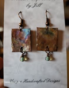 a pair of square earrings with pearls hanging from it's earwires on top of a card