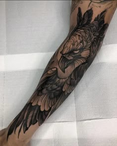 a man's arm with black and grey tattoos on it, including an eagle