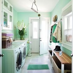 a washer and dryer in a small room with green walls, flooring and white cabinets