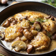 a pan filled with chicken and mushrooms covered in gravy on top of a wooden table