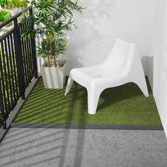 a white chair sitting on top of a green carpet next to a potted plant