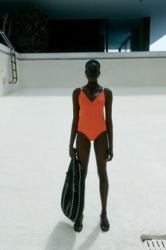 a woman in an orange swimsuit holding a black purse