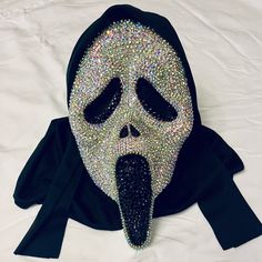 a person wearing a mask on top of a white bed covered in lots of beads