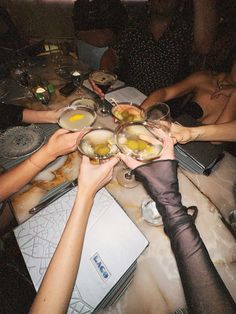 several people sitting at a table with wine glasses in their hands and food on the plates