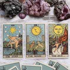 four tarot cards with the sun and moon on them, surrounded by crystals and rocks