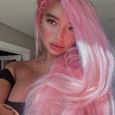 a woman with pink hair is posing for the camera