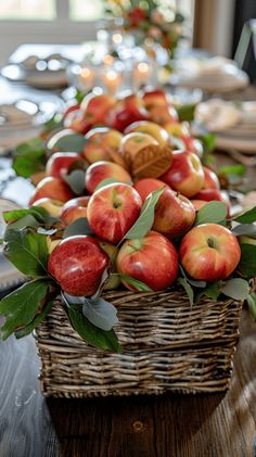 an arrangement of apples in a wicker basket on a dining room table with place settings