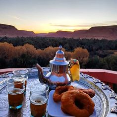 two donuts are sitting on a tray with drinks in front of the desert view