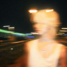 blurry image of a man walking down the street at night with buildings in the background