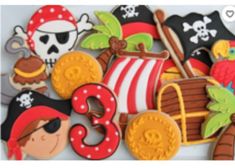 decorated cookies are arranged in the shape of pirate's chest and ship, on a plate