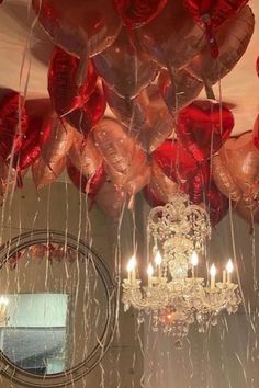 a chandelier hanging from the ceiling filled with red heart shaped balloons