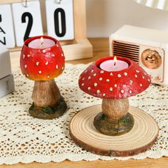 two red candles sitting on top of a wooden table next to a clock and other items