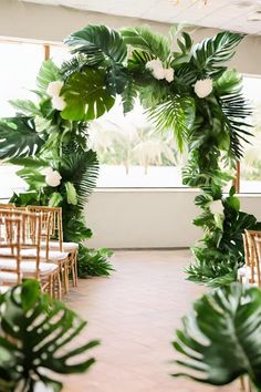 an indoor ceremony with chairs and greenery