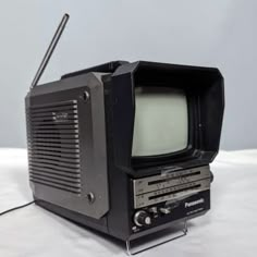 an old fashioned television sitting on top of a white sheet covered table next to a radio