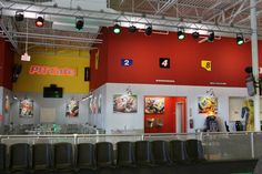 the inside of a fast food restaurant with red walls and green lights hanging from the ceiling