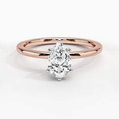 a yellow gold engagement ring with a pear shaped diamond in the center, on a white background