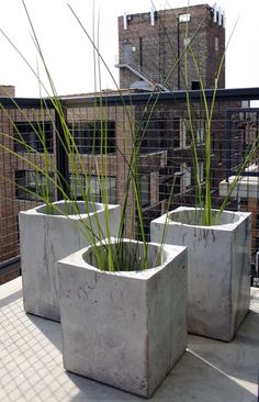 two cement planters with grass in them on a roof top deck overlooking the city