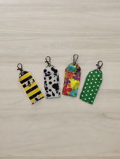 four keychains with different designs on them sitting on top of a white surface