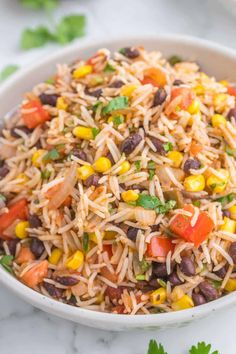 a white bowl filled with mexican rice and beans, garnished with cilantro