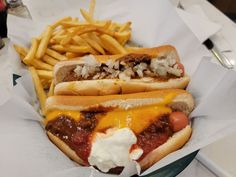 two chili cheese dogs with fries on the side