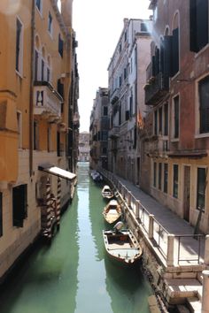 two boats are docked in the narrow canal