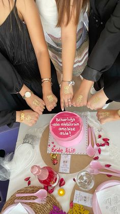 a group of people standing around a pink cake