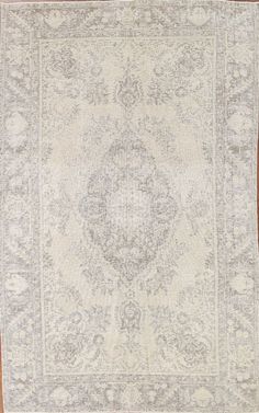 an antique rug is displayed on a wooden floor in front of a white and gray background