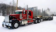 a red semi truck driving down a snow covered road