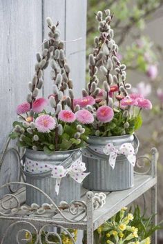 two tin cans filled with pink flowers on top of a table