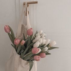 a white bag with pink and white tulips hanging on the door handle,