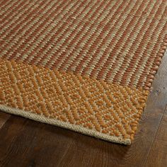 an orange and beige area rug on a wooden floor