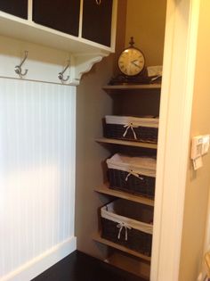 an empty closet with several baskets and a clock on the wall next to it's shelves