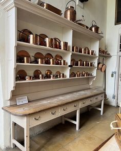 an old kitchen with many pots and pans on the shelves, including one bench