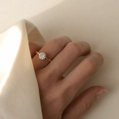 a woman's hand with a diamond ring on top of her finger, against a white background