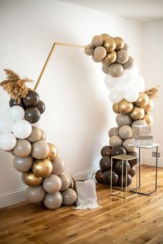 balloons are arranged in the shape of an arch with gold and white balloons on it