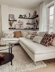 a living room filled with lots of furniture next to a wall mounted shelf full of pictures