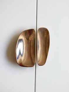 a close up of two door handles on a white wall with a mirror in the background