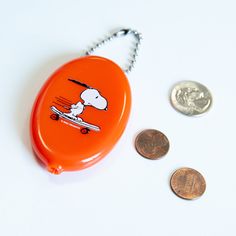 an orange object with a cartoon character on it next to two coins and a coin clip