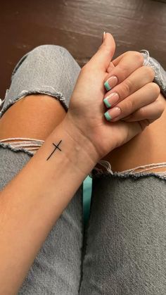 a woman's arm with a cross tattoo on it