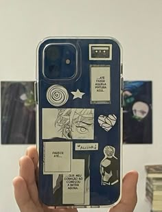 a person holding up a cell phone case that has pictures on it and other things in the background