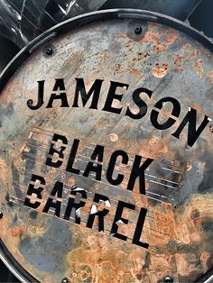 a sign that says jameson black barrel on the side of a metal tank with rusted paint