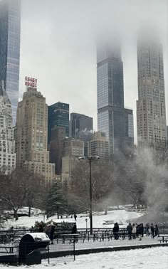 the city skyline is covered in snow as people walk by on a cold winter day