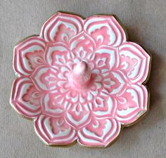 a pink and white flower shaped dish sitting on top of a table next to a wall