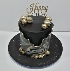 a black and silver birthday cake with gold decorations